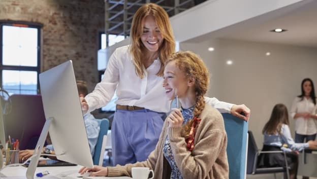 two women collaborating at a desktop computer